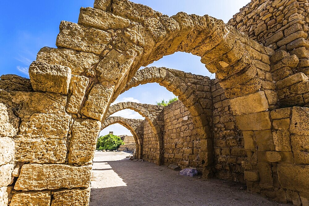 Picturesque ruins of the ancient city of Caesarea. Israel. Sunny spring day. Arched passage - covered street of Port of Caesarea. Concept of ecological and historical tourism