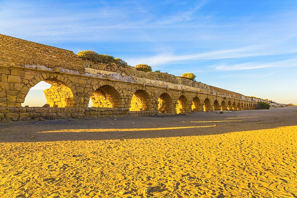 High aqueduct, built under the reign of Herod the Great. Concept of active, ecological and historical tourism. Fantastic sunset on the Mediterranean coast in Caesarea