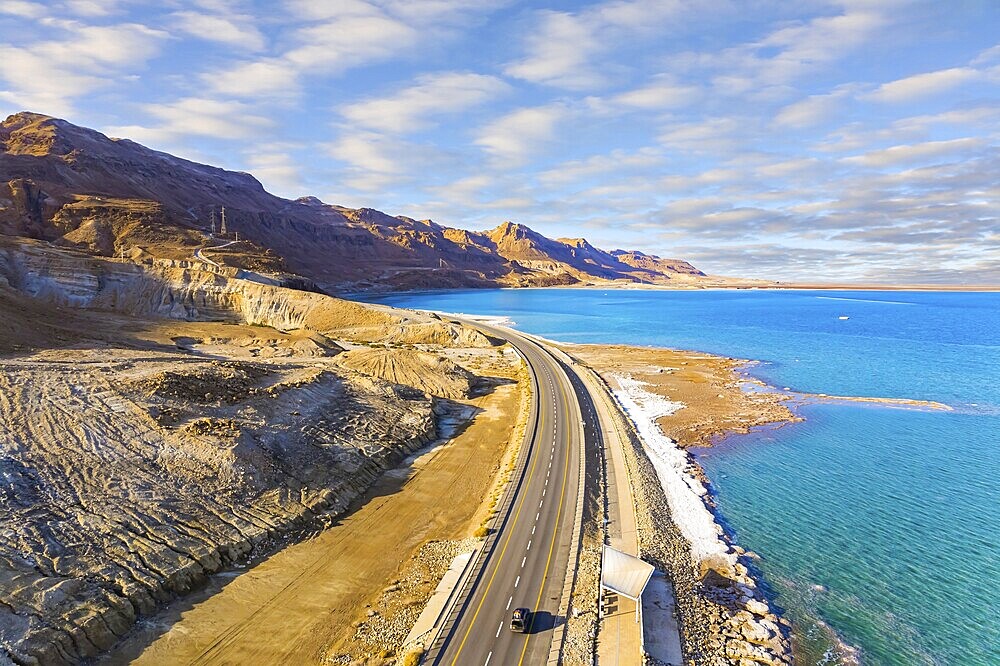 Sunset. Dead Sea photographed from a drone. Evaporated salt was deposited along the shore. Asphalt highway runs along the seashore. The winter in Dead Sea