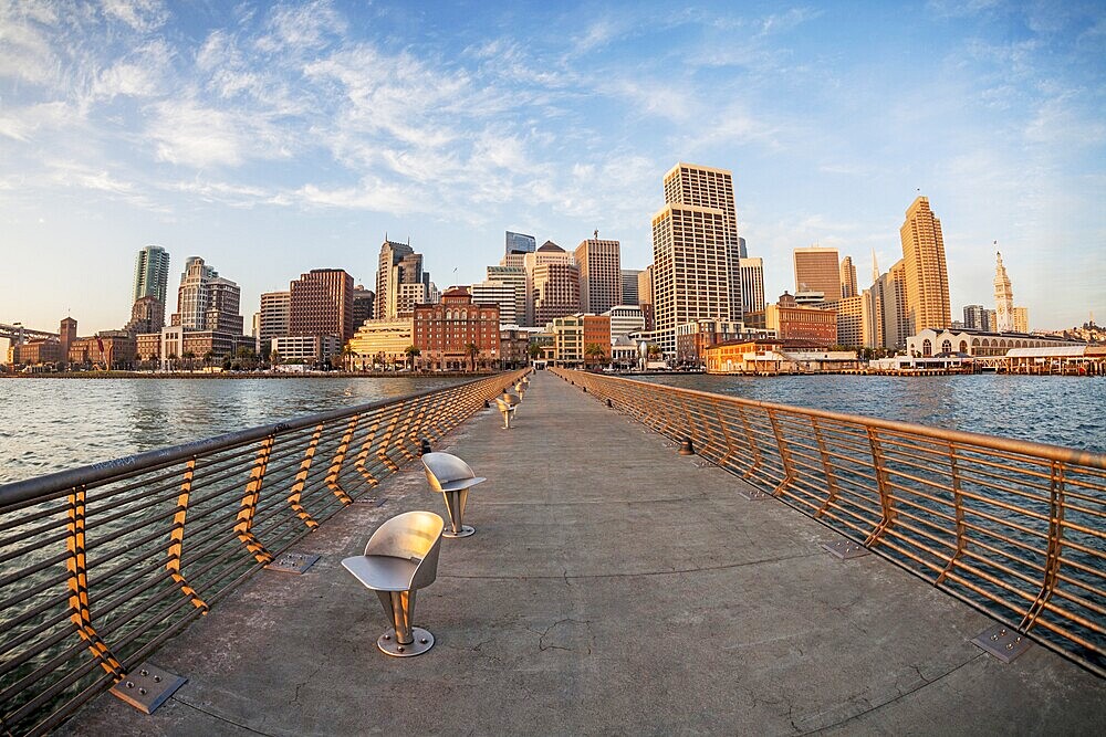 San Francisco cityscape with Ferry Terminal at sunrise from Pier 14 with metal swivel chairs, distorted fish eye perspective from Pier 14