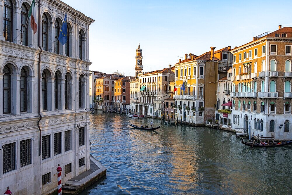 View of the Grand Canal with gondoliers at sunset, picturesque evening mood with palazzos on the canal and church tower of the Chiesa Parrocchiale dei Santi Apostoli, view from the Rialto Bridge, Venice, Veneto, Italy, Europe