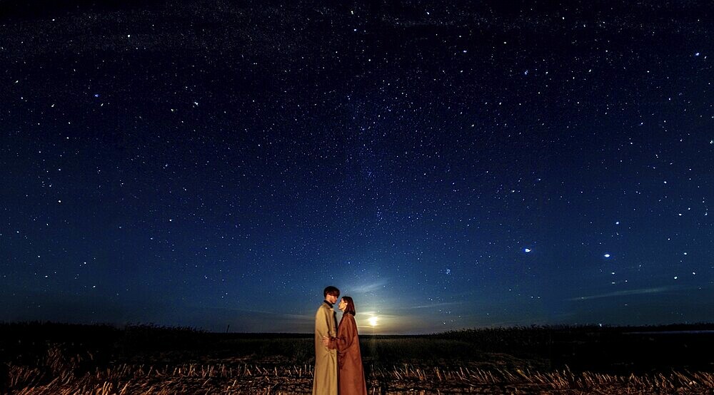 A couple under a vast starry night sky, evoking a sense of romance and wonder