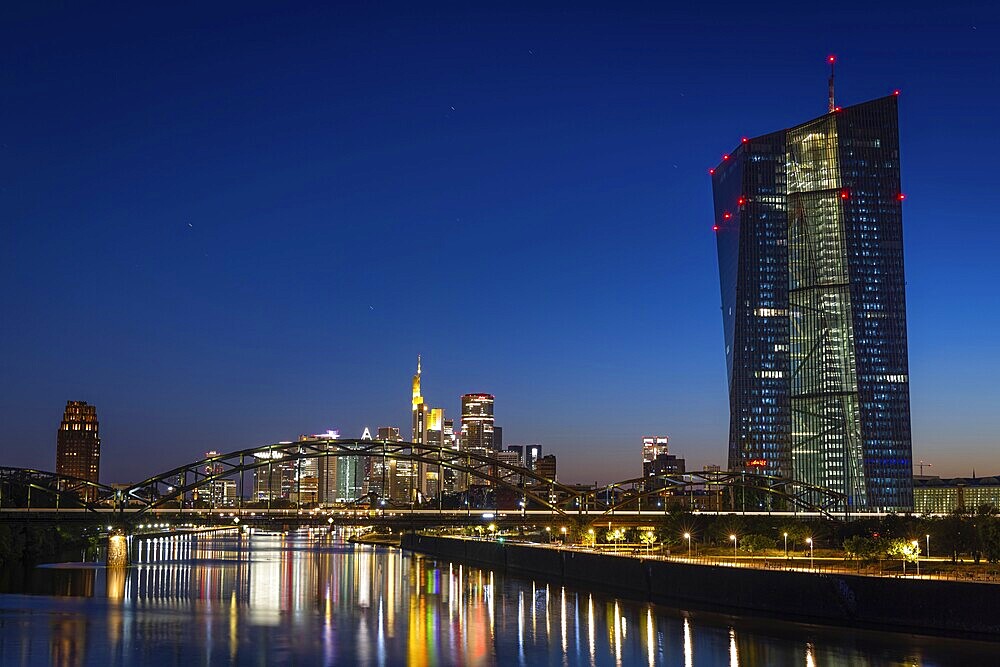 The European Central Bank (ECB) and the Frankfurt banking skyline are reflected in the calm waters of the Main at blue hour, Osthafen, Frankfurt am Main, Hesse, Germany
