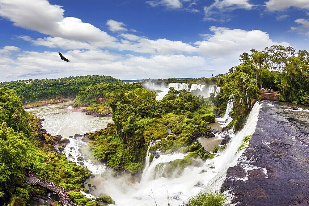 The tropical sun illuminates the water of waterfalls Iguazu. Picturesque basaltic ledges form the famous waterfalls. Travel to Argentina. The concept of active and exotic tourism