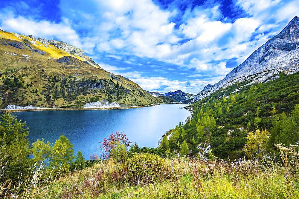 Glacial lake with clear cold water. Mountain Lake Lago di Fedaia, Dolomites. The magic and harmony of the Dolomites. The concept of ecological and extreme tourism