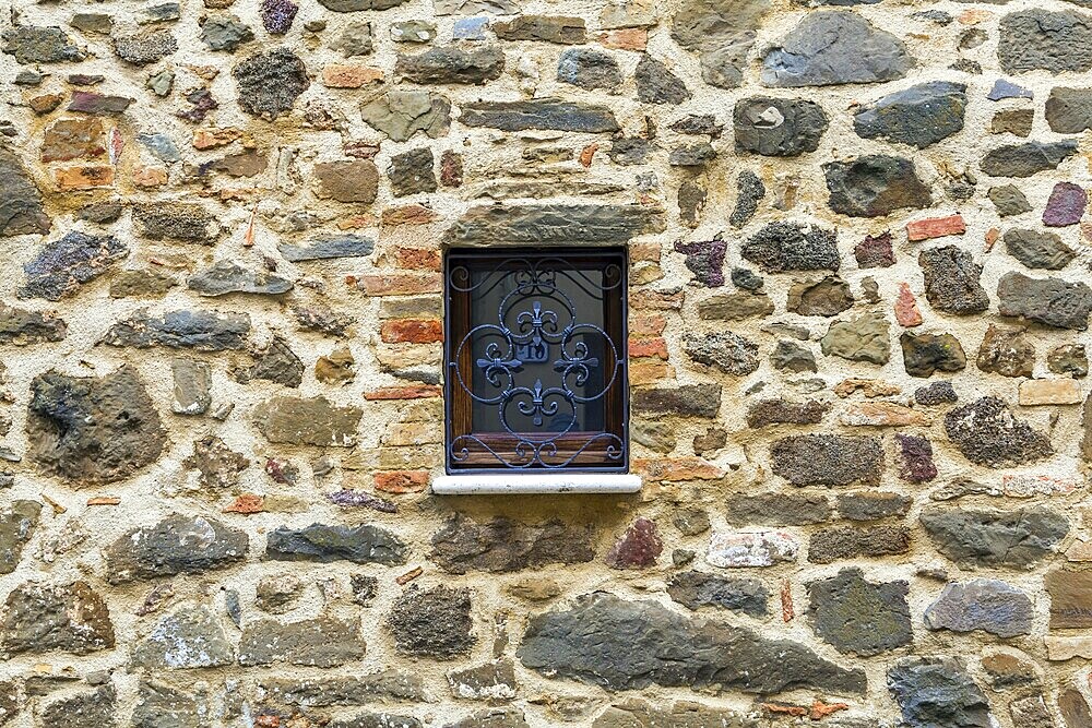 Cloudy autumn day in Tuscany. The small town of Montalcino. The beautiful decor element of a small window - metal window grill. The concept of cognitive, active and photo tourism
