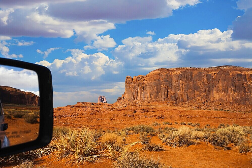 Monument Valley is a unique geological formation. The USA. Huge masses of red sandstone - outliers on the Navajo Indian Reservation. Reflection in a car mirror. The concept of photo tourism