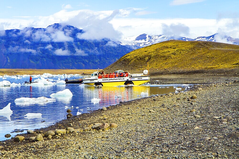 ICELAND, SCAFTAFETL PARK, ICE LAGOON JOKULSAURLOUN - July 10, 2014: Yellow boat for tourists. The icebergs and ice floes reflected in the water. The concept of northern and photo tourism