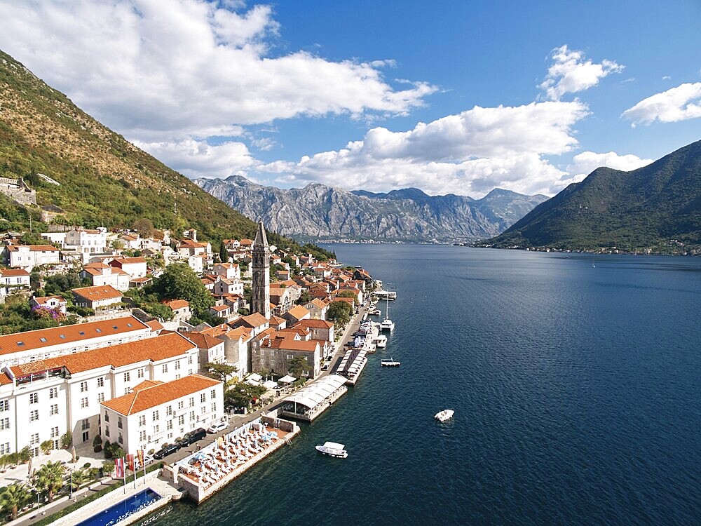 Swimming pool and private beach on the shore of the Bay of Kotor overlooking ancient houses. Perast, Montenegro. Drone.