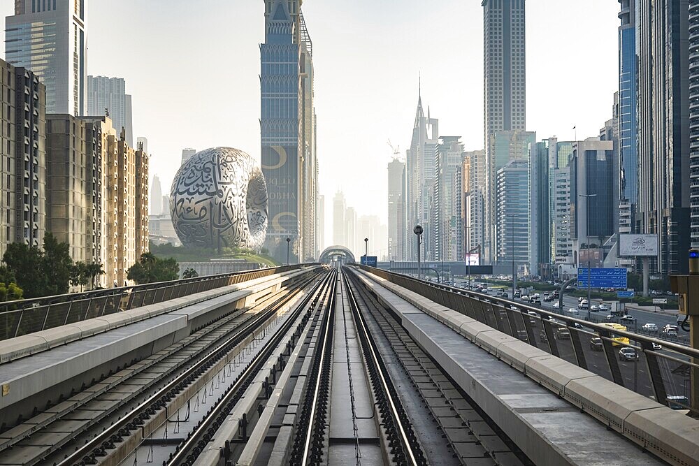 Dubai, UAE - 11.3.2022: Dubai Metro rail with skyscrapers and Museum of the Future in Dubai in the frame. Dubai Cityscape skyline with modern urban transit system
