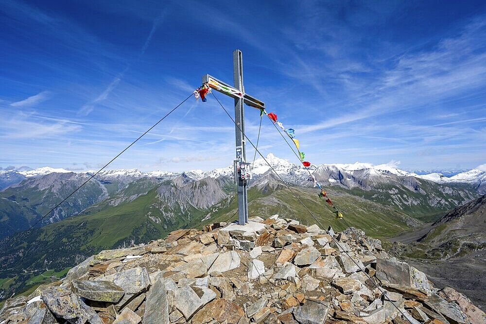 Böses Weibl summit with summit cross and colourful prayer flags, view of picturesque mountain landscape with snow-covered summit of the Großglockner, Wiener Höhenweg, Schober group, Hohe Tauern National Park, Carinthia, Austria