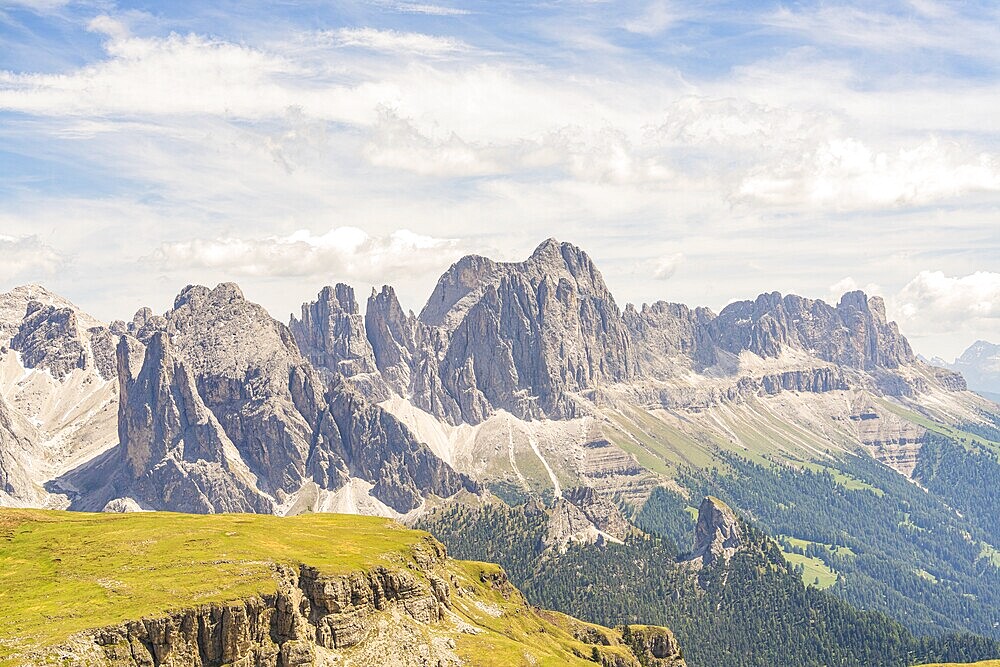 Imposing mountain range with dramatic sky and clouds, green plains below, hike to the Schlehrn, Alpe di Siusi, Dolomites, South Tyrol, Italy