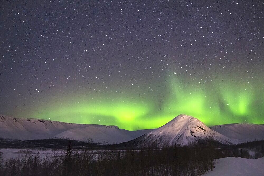 Night Starry Sky and Green Northern Lights in Snowy Mountains at Winter Night
