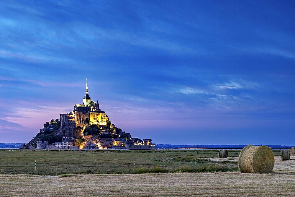 Mont Saint-Michel at dusk, illuminated with straw bales in the foreground, Mont Saint Michel in Normandy, France