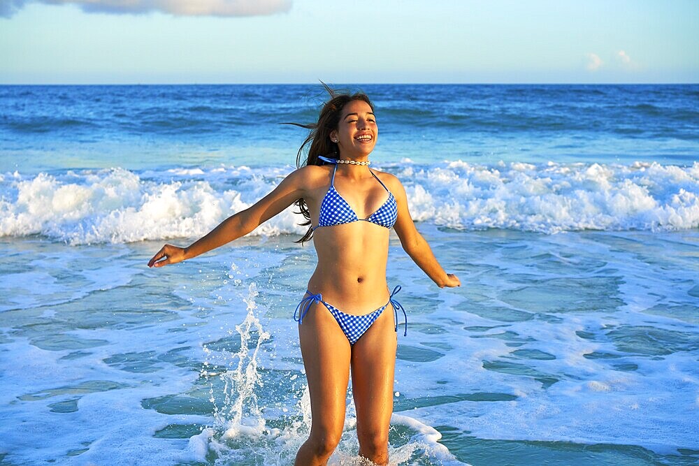 Latin beautiful bikini girl happy jumping in Caribbean beach sunset