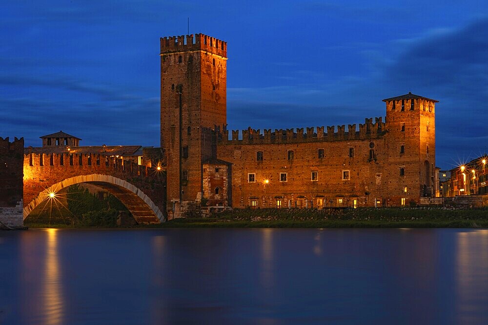 Majestic castle with bridge illuminated against the night sky with mirror-smooth river, at the blue hour, above the river Adige, Museo di Castelvecchio, Ponte Scaligero, Verona, Veneto region, Italy