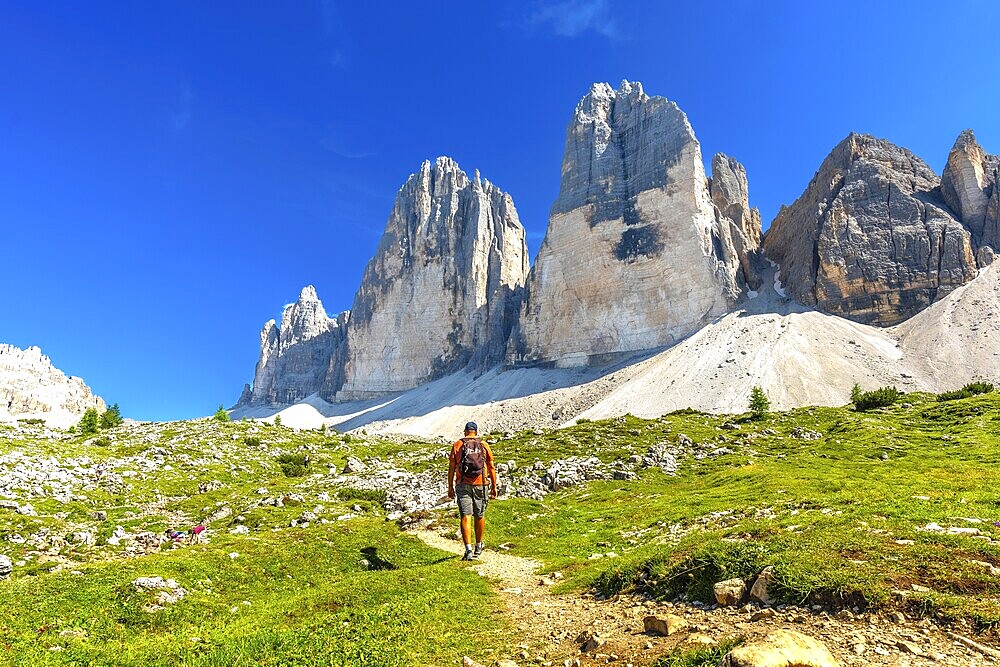 Tourist enjoying a summer hike on a scenic trail leading to the majestic tre cime di lavaredo peaks in the dolomites, Italy