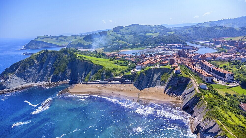 Breathtaking aerial perspective of zumaia's dramatic cliffs, golden beaches, and charming town nestled along the vibrant bay of biscay coastline in the basque country, Spain.