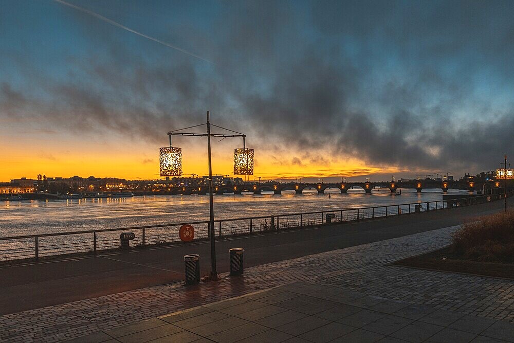 Scenic view of bordeaux cityscape illuminating at sunset over garonne river with pont de pierre bridge in the background