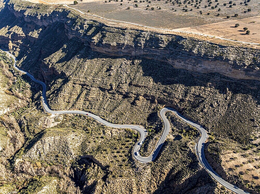 Deep canyon at the Gorafe desert, winding road to village Gorafe, aerial view, Gorafe Desert, UNESCO Granada Geopark, Granada province, Andalusia, Spain