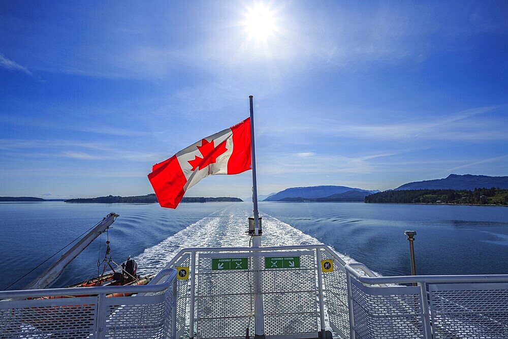 A Canadian flag flying on the stern of a BC Ferries vessel sailing from Alert Bay to Port McNeill, British Columbia, Canada