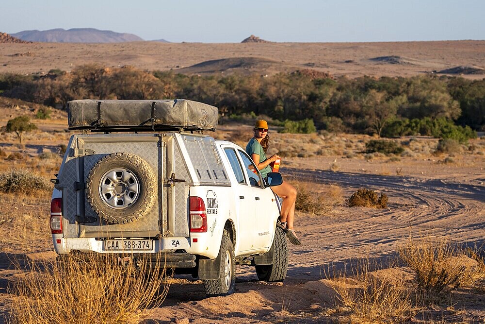 Tourist with off-road car on a sandy track, rock formation, Brandberg, Damaraland, Namibia