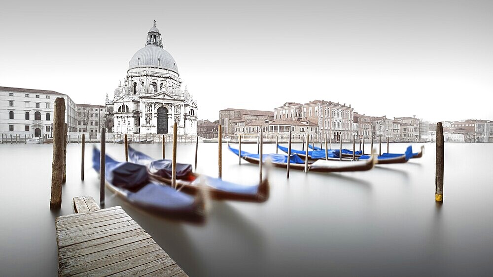 Gondolas moored on the Grand Canal with the Cathedral of Santa Maria della Salute in the background in Venice, Italy