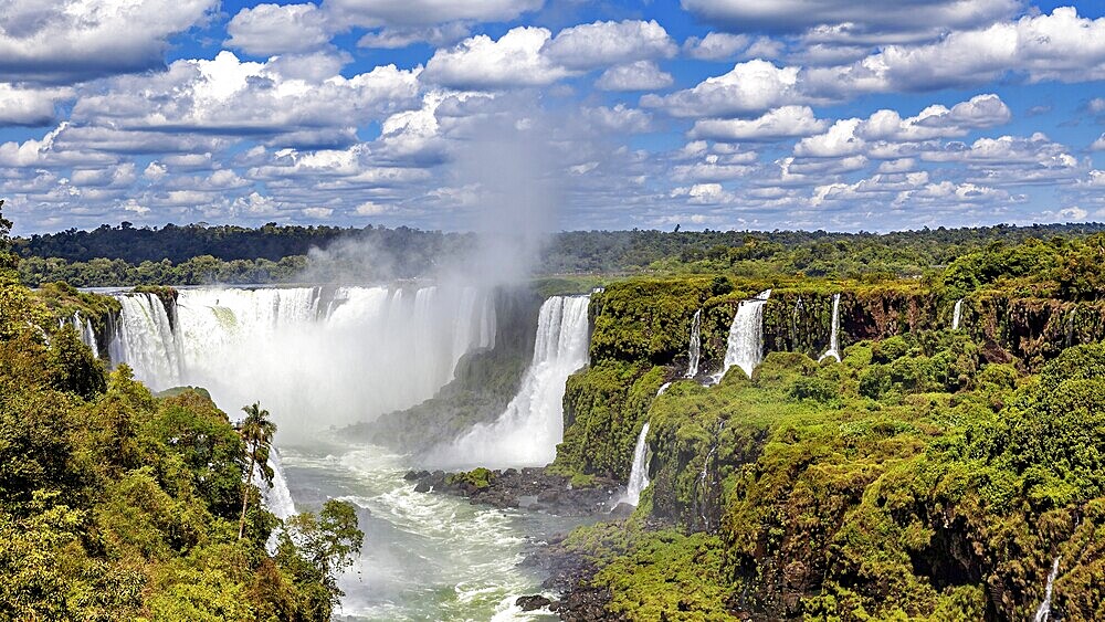Waterfalls in the dense jungle, surrounded by lush greenery under a cloudy sky, The Iguazu Falls between Argentina and Brazil