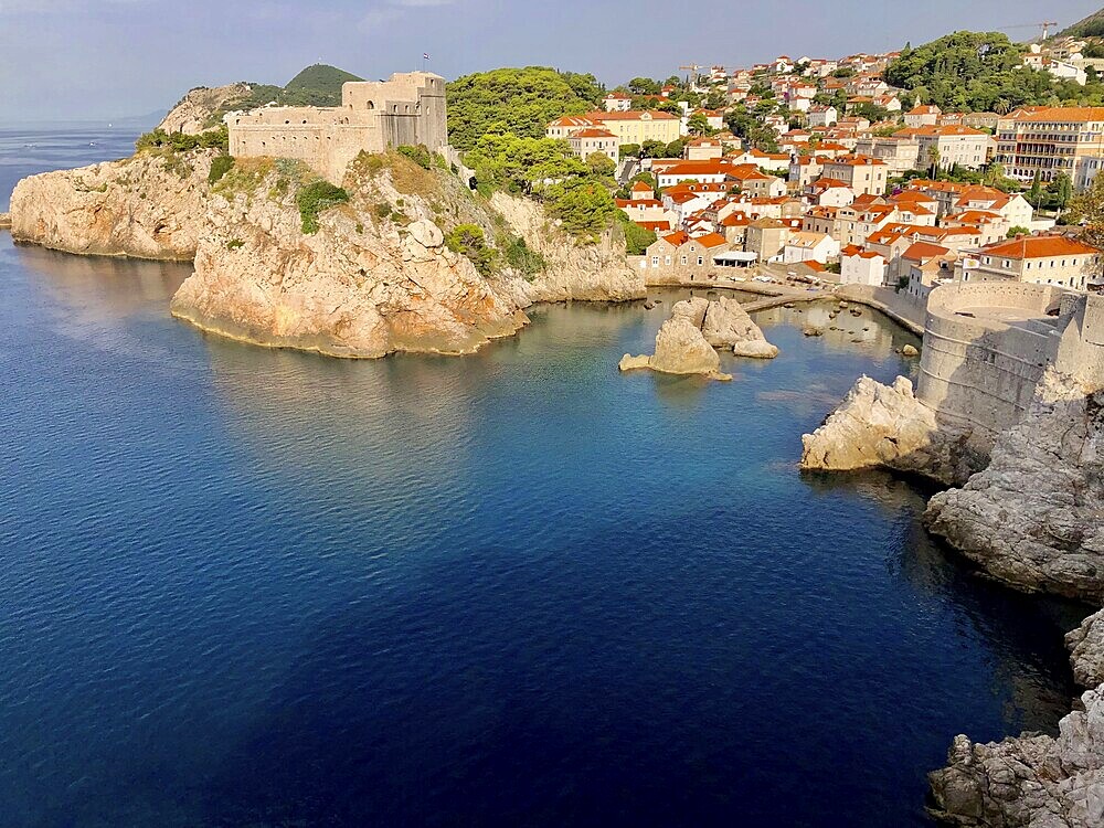 Panorama of a rocky coast with fortress, buildings and deep blue sea in sunny weather, Dubrovnik, Croatia