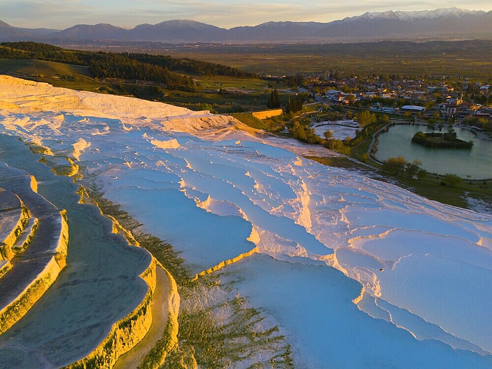 Panorama of terraces and water with mountain backdrop in the soft light of dusk, aerial view, sinter terraces, limestone sinter terraces, travertine terraces, Pamukkale, Denizli, UNESCO World Heritage Site, Anatolia, Turkey