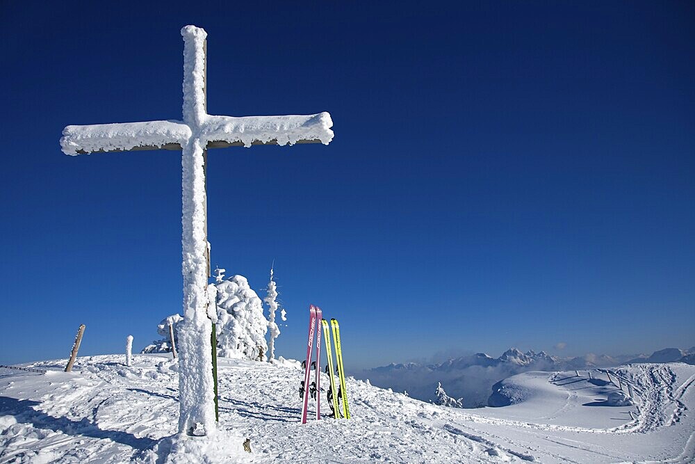 Snow-covered summit cross and touring skis on the summit of the Reuterwanne. in the distance the Tannheimer mountains, Allgäu Alps, Jungholz, Tyrol, Austria