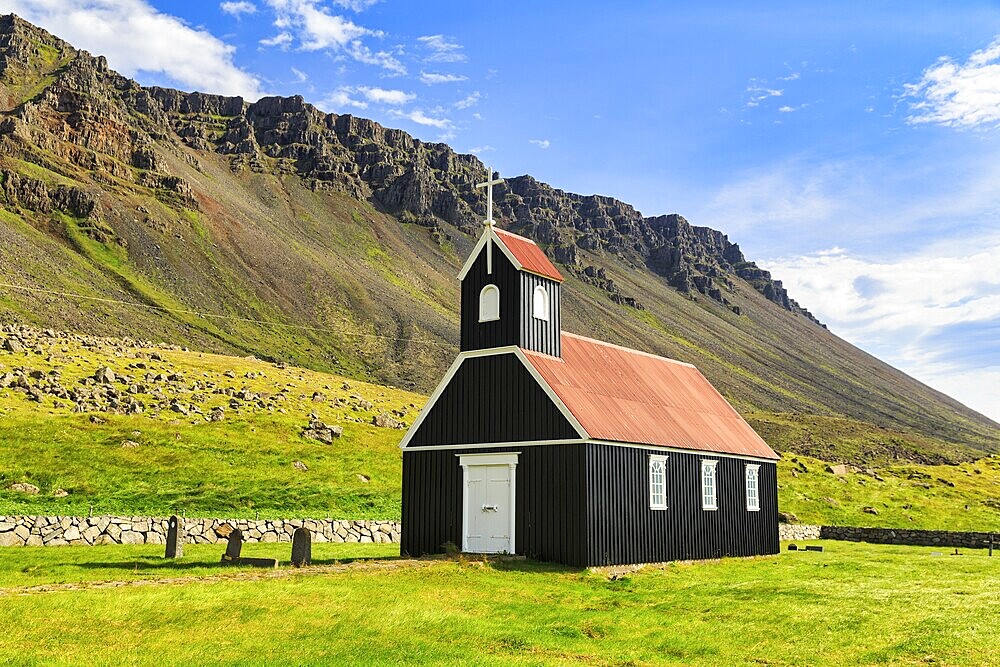 Black wooden church in a meadow in front of a cliff, Saurbæjarkirkja, Saurbær, Rauðisandur, Raudisandur, near Patreksfjördur, Westfjords, Iceland