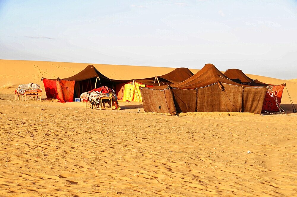 Traditional tents in the desert under warm sunlight, sand dunes of Erg Chebbi, Erfoud, Middle Atlas, Morocco