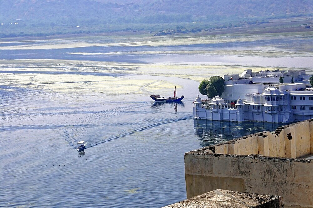 Lake Pichola with Lake Palace (Jag Niwas), Udaipur, Rajasthan, North India, Asia, A palace on the lake with boats on calm water and mountains in the background, India
