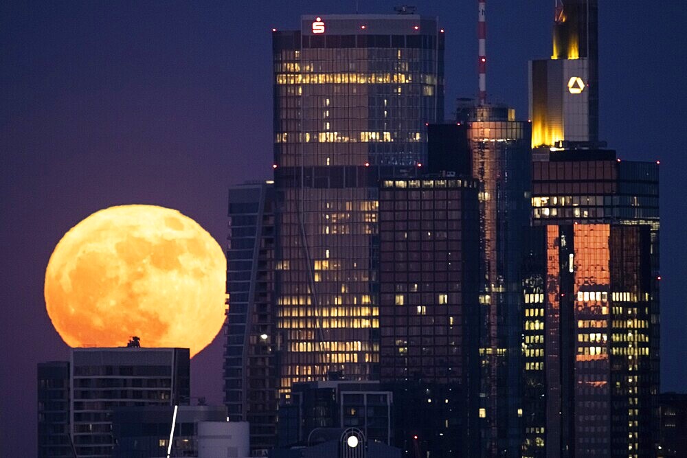 The full moon passes behind the Frankfurt banking skyline, Frankfurt am Main, Hesse, Germany