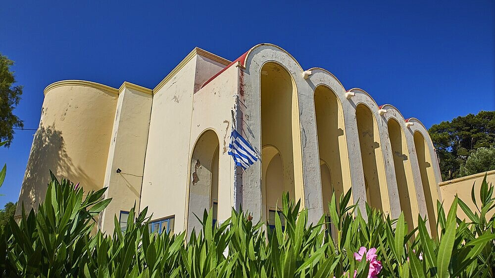 Primary school, Building with arches and Greek flag, surrounded by plants, Armando Bernabiti, Historicism, Rationalism, Art Deco, Rationalism, Rodolfo Petraco, Fascism, Portolago, Lakki, Leros, Dodecanese, Greek Islands, Greece