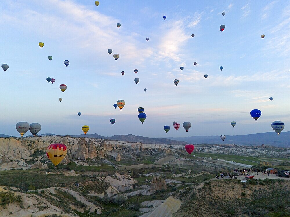 Many colourful hot air balloons float over a vast Turkish landscape in the early morning, aerial view, Göreme National Park, Göreme Tarihî Millî Parki, Nevsehir Province, Nevsehir, Cappadocia, Cappadocia, Kapadokya, Cappadocia, Central Anatolia, Turkey