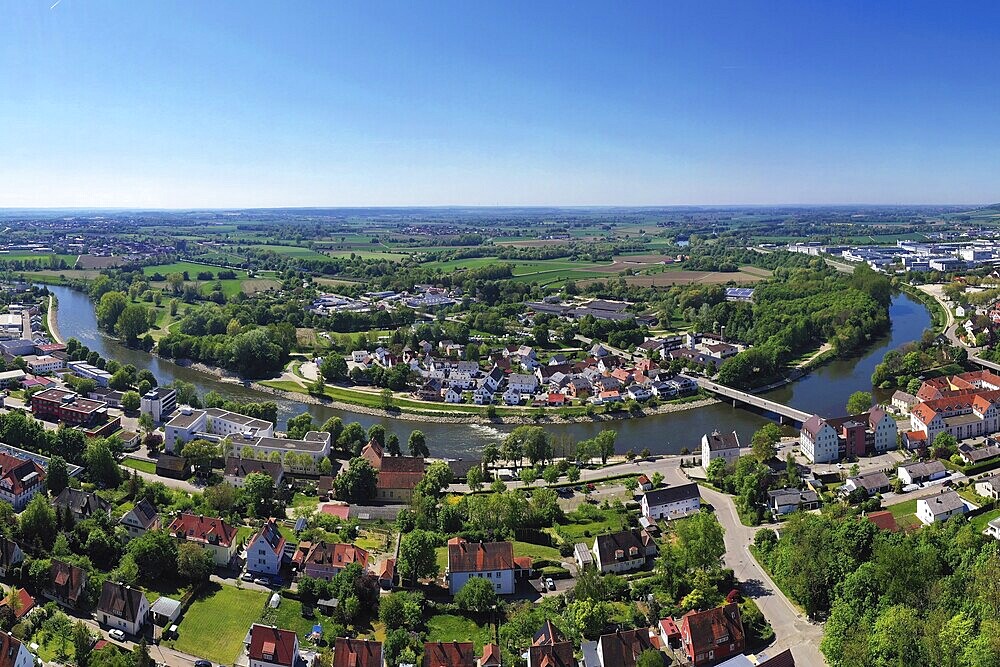 Fascinating aerial view of Donauwörth with its characteristic red roofs and historic buildings. A striking building with a tower stands out in the foreground, surrounded by well-tended green spaces and trees. The town stretches along the rolling hills and offers a picturesque atmosphere with idyllic streets, a historic townscape and expansive landscapes. Donauwörth, Swabia, Bavaria, Germany