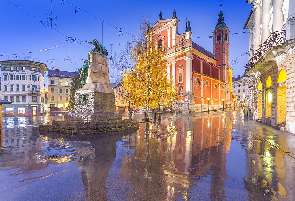 Reflections of the ornate facade of the Franciscan Church of the Annunciation and Preseren Monument in Plaza Presernov at dusk, Ljubljana, Slovenia, Europe