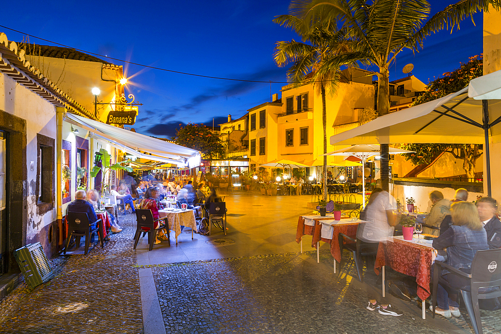 View of cafe in cobbled street in old town at dusk, Funchal, Madeira, Portugal, Europe