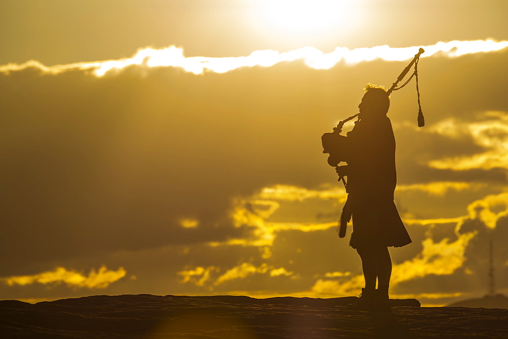 View of lone piper at at sunset on Curbar Edge, Curbar, Hope Valley, Peak District National Park, Derbyshire, England, United Kingdom, Europe