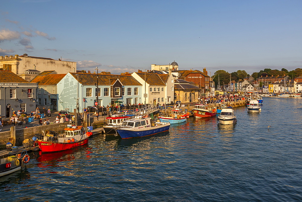 View of boats in the Old Harbour and quayside houses at sunset, Weymouth, Dorset, England, United Kingdom, Europe