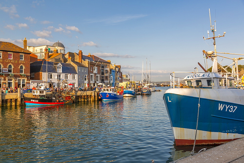 View of boats in the Old Harbour and quayside houses at sunset, Weymouth, Dorset, England, United Kingdom, Europe