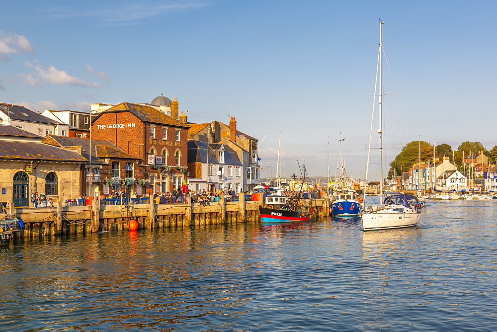 View of boats in the Old Harbour and quayside houses at sunset, Weymouth, Dorset, England, United Kingdom, Europe