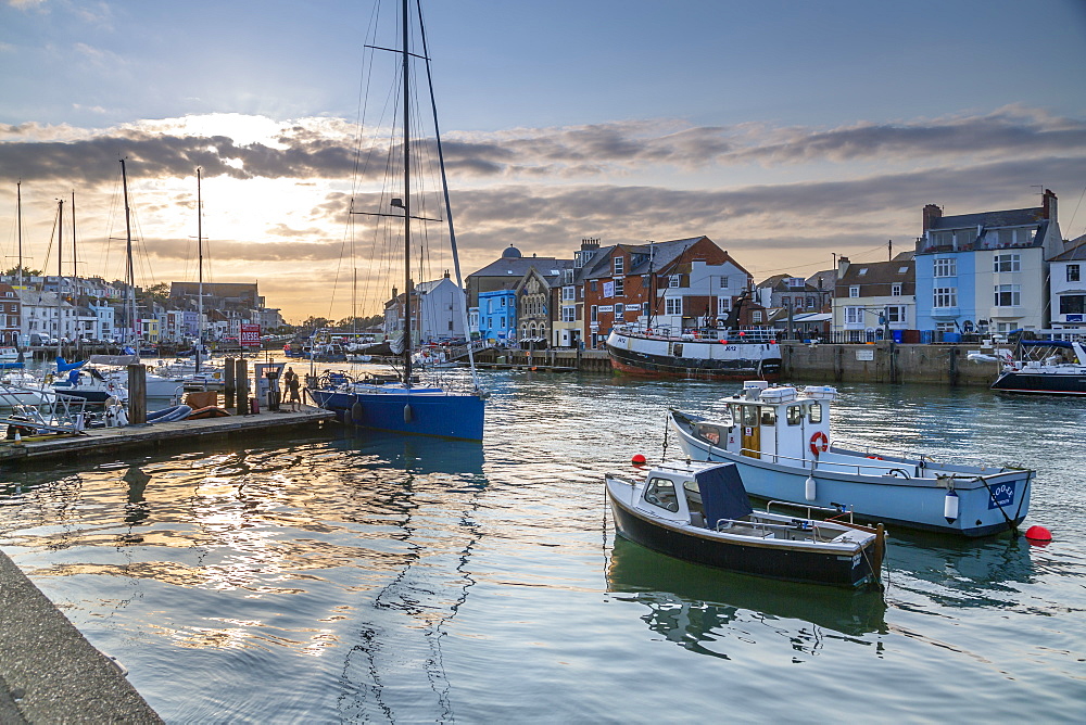 View of boats in the Old Harbour and quayside houses at sunset, Weymouth, Dorset, England, United Kingdom, Europe