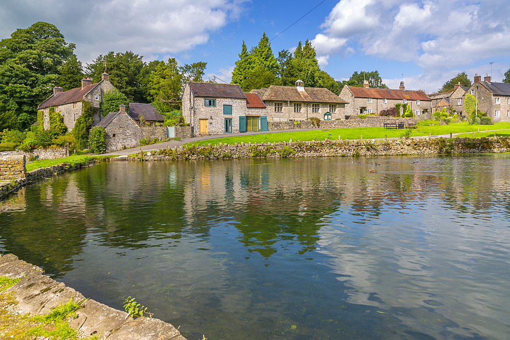 View of cottages reflecting in village pond, Tissington, Peak District National Park, Derbyshire, England, United Kingdom, Europe