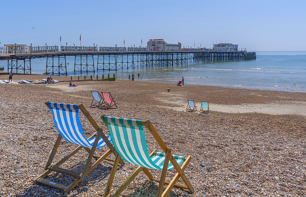 View of Worthing Pier and colourful deckchairs on Worthing Beach, Worthing, West Sussex, England, United Kingdom, Europe