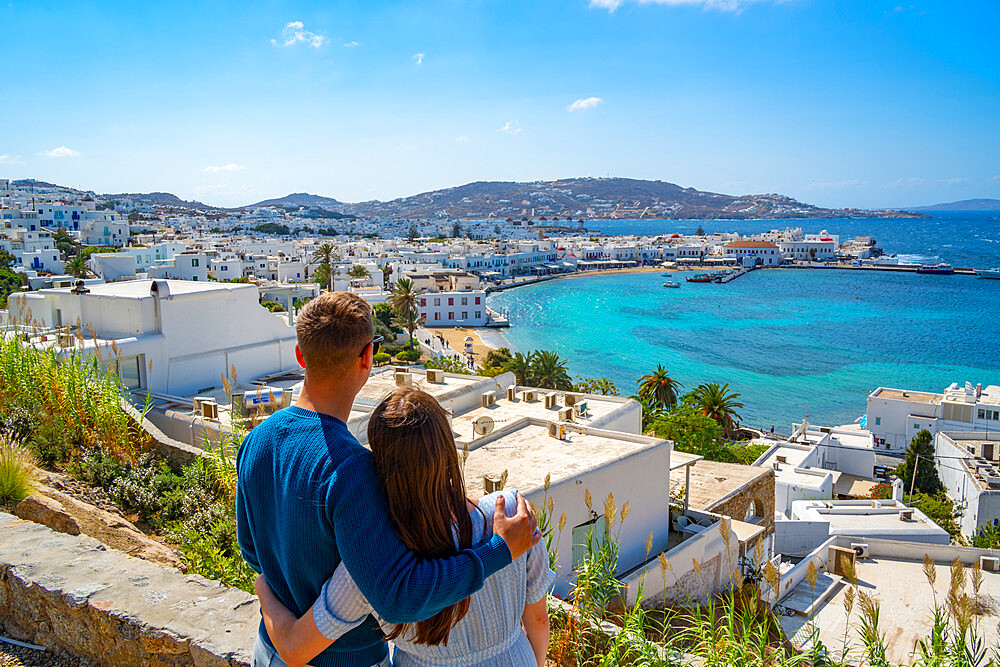 Young couple with elevated view of flour mills and town, Mykonos Town, Mykonos, Cyclades Islands, Greek Islands, Aegean Sea, Greece, Europe