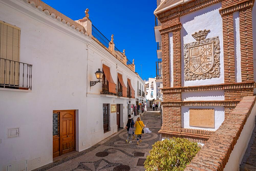 View of white washed houses and shoppers on narrow street, Frigiliana, Malaga Province, Andalucia, Spain, Europe