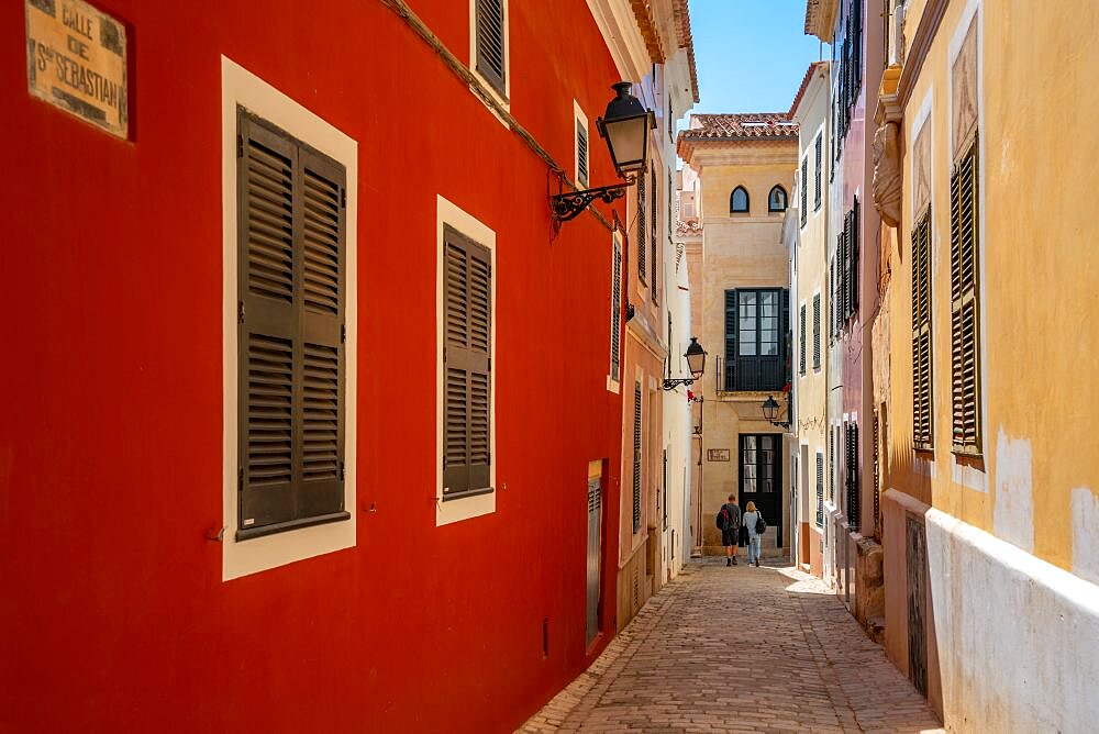 View of couple walking down pastel coloured street in historic centre, Ciutadella, Memorca, Balearic Islands, Spain, Europe